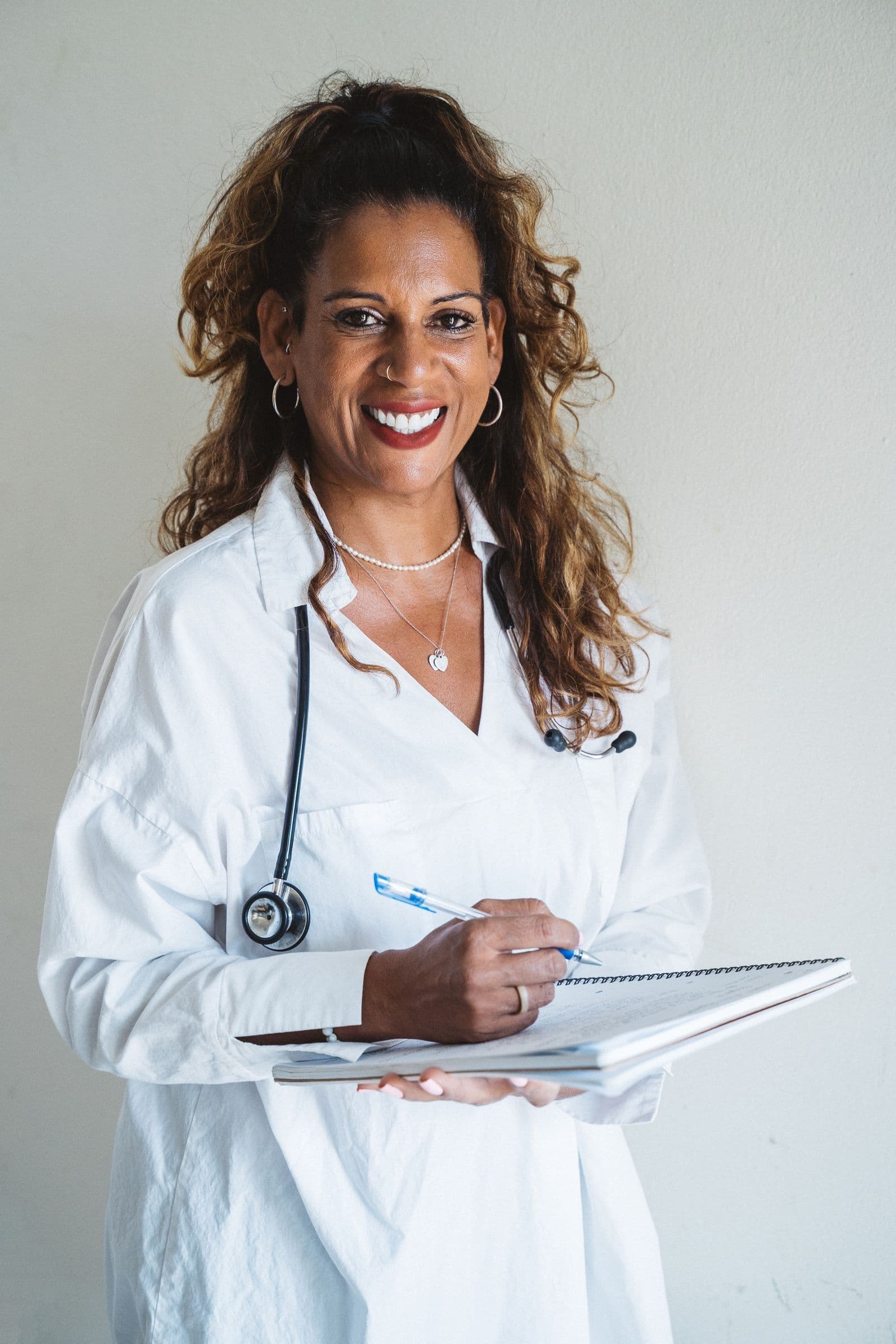 Model wearing a white coat and holding a notebook
