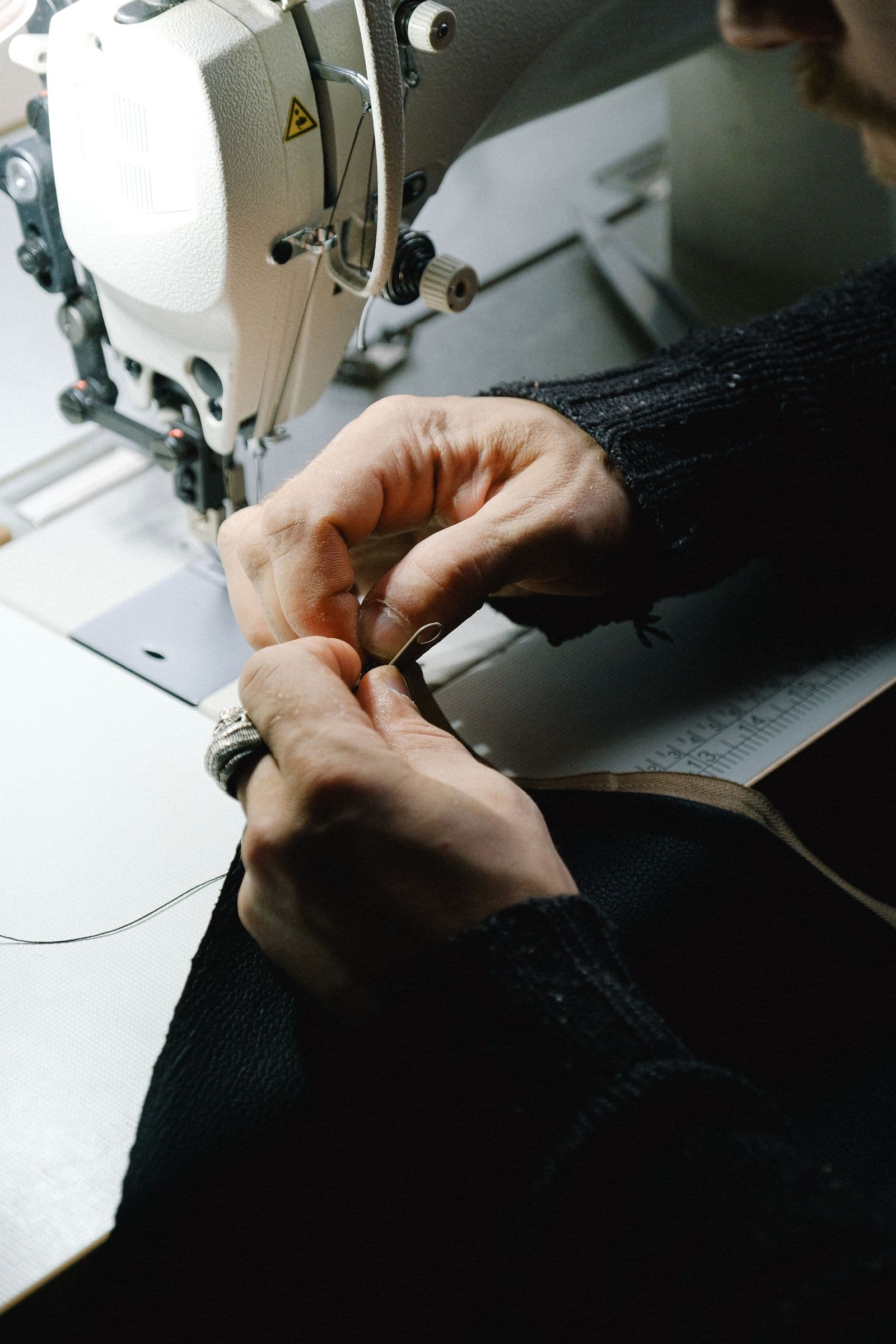 Hands holding dark fabric beside a sewing machine