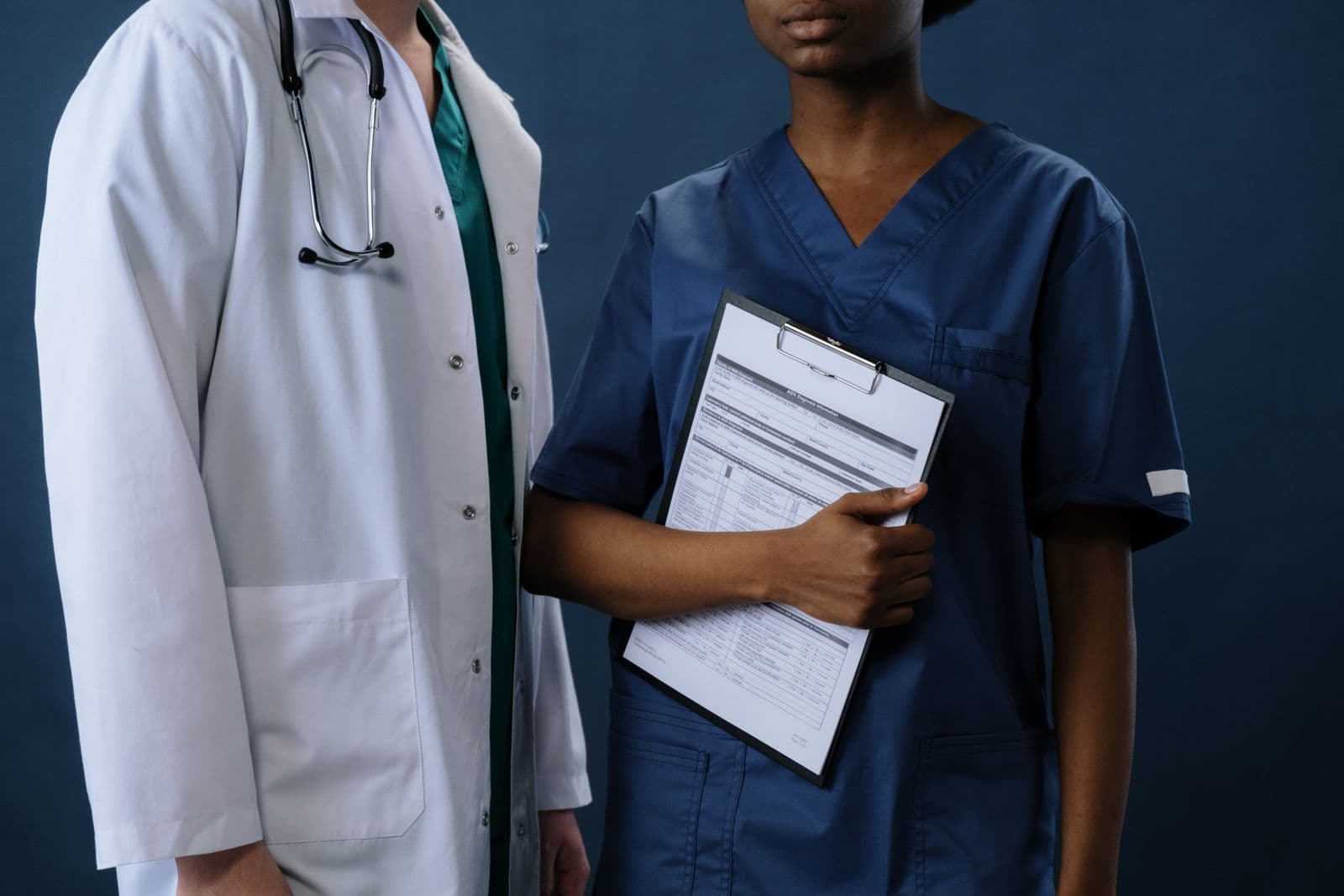 Two models wearing medical-style uniforms against a navy studio background